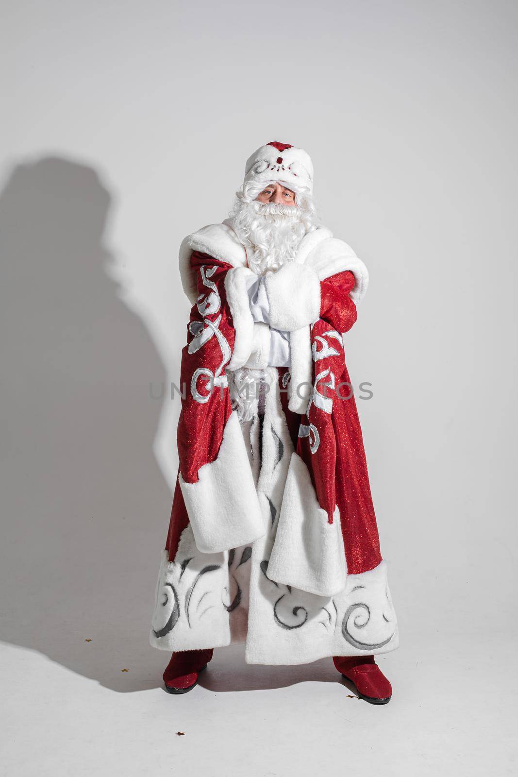 picture of an old caucasian father frost in long warm coat, red mittens and a hat looks to the camera by StudioLucky