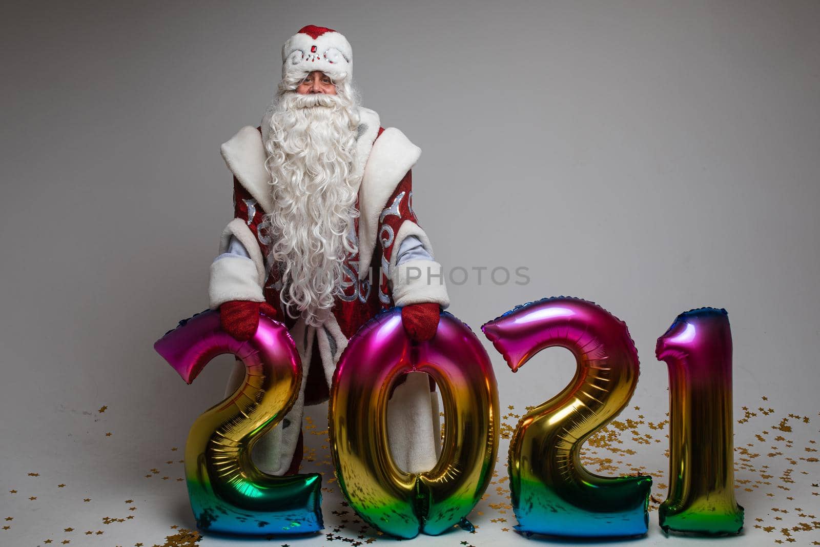 Santa Claus with colorful balloons in shape of 2021 on gray background with copy space, xmas and new year celebration by StudioLucky