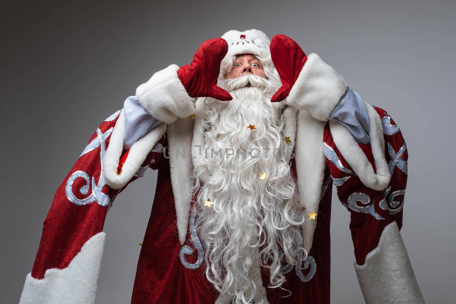 Santa Claus put on hands to mouth to congratulate with xmas and happy new year, studio portrait on gray background by StudioLucky