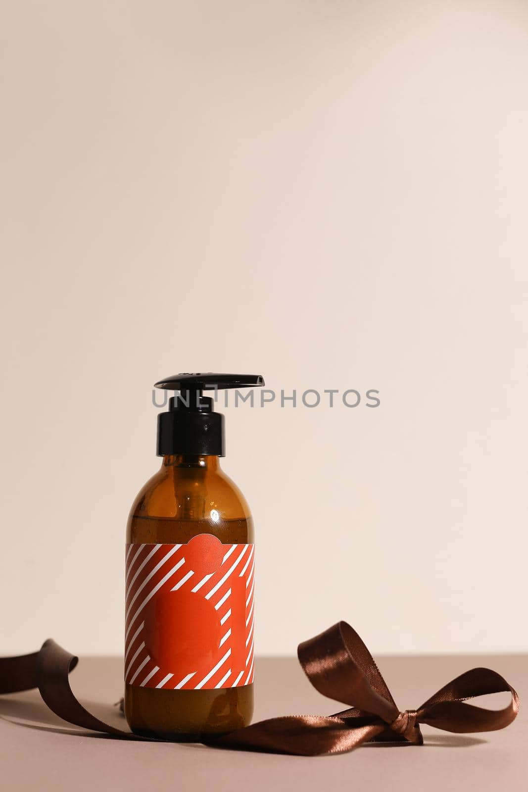 Beauty natural skincare products development concept. Dermatologist cosmetic skincare bottle with pump dispenser and organic ingredient on neutral background with copy pace text. Ribbon for present