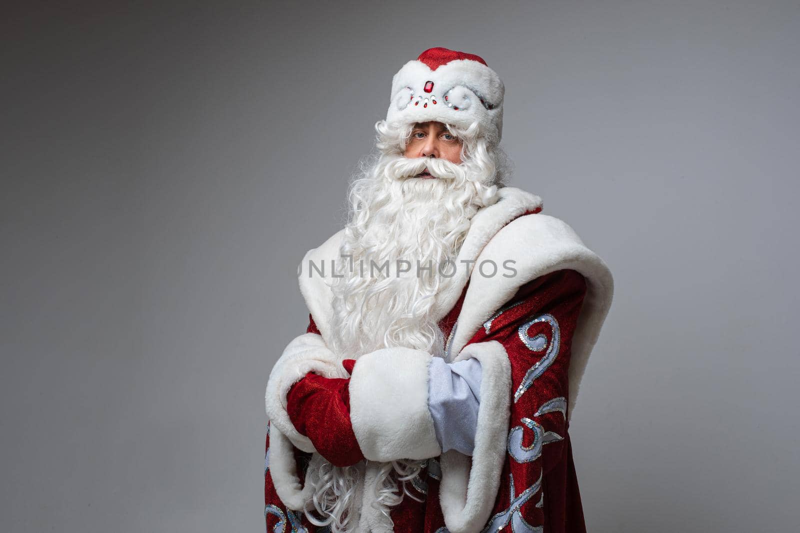 Tired Santa Claus posing on gray studio background with copy space for holiday xmas and new year advertising by StudioLucky