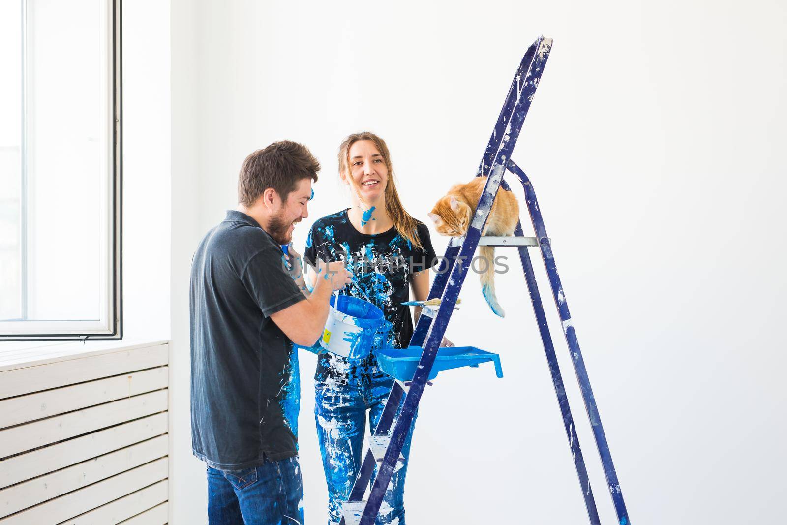 Teamwork and repair concept - young couple with cat doing a renovation in new apartment.