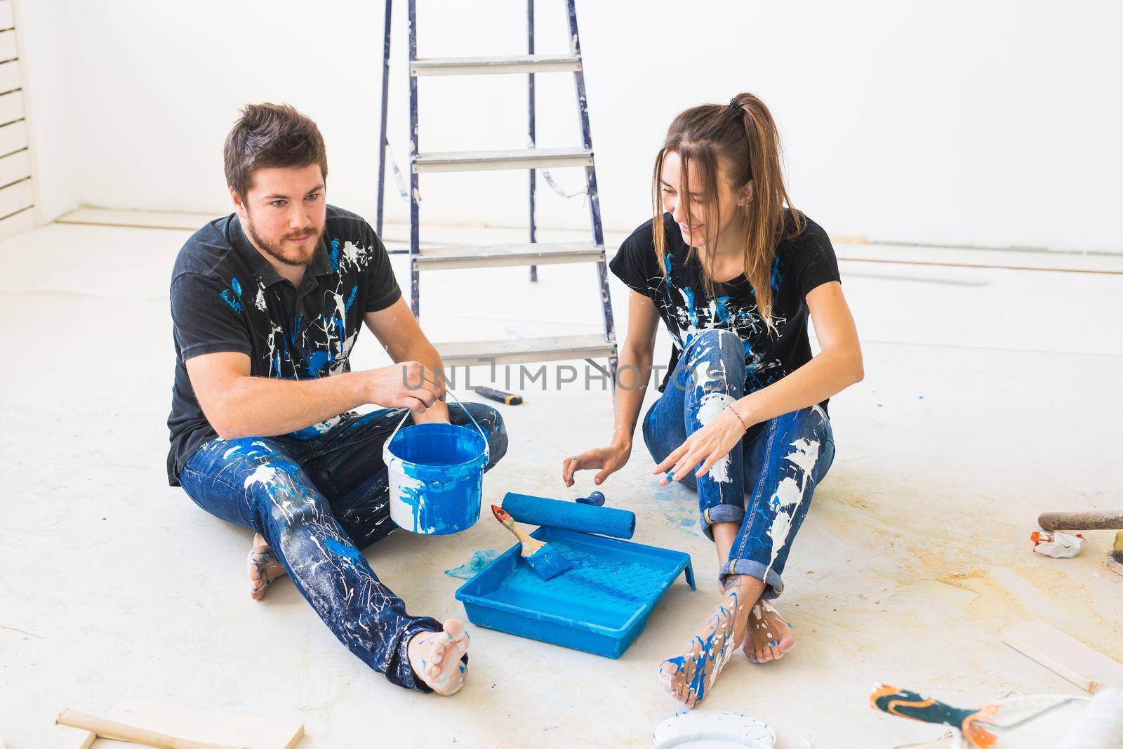 Repair, renovation and people concept - portrait of happy couple pour paint by Satura86