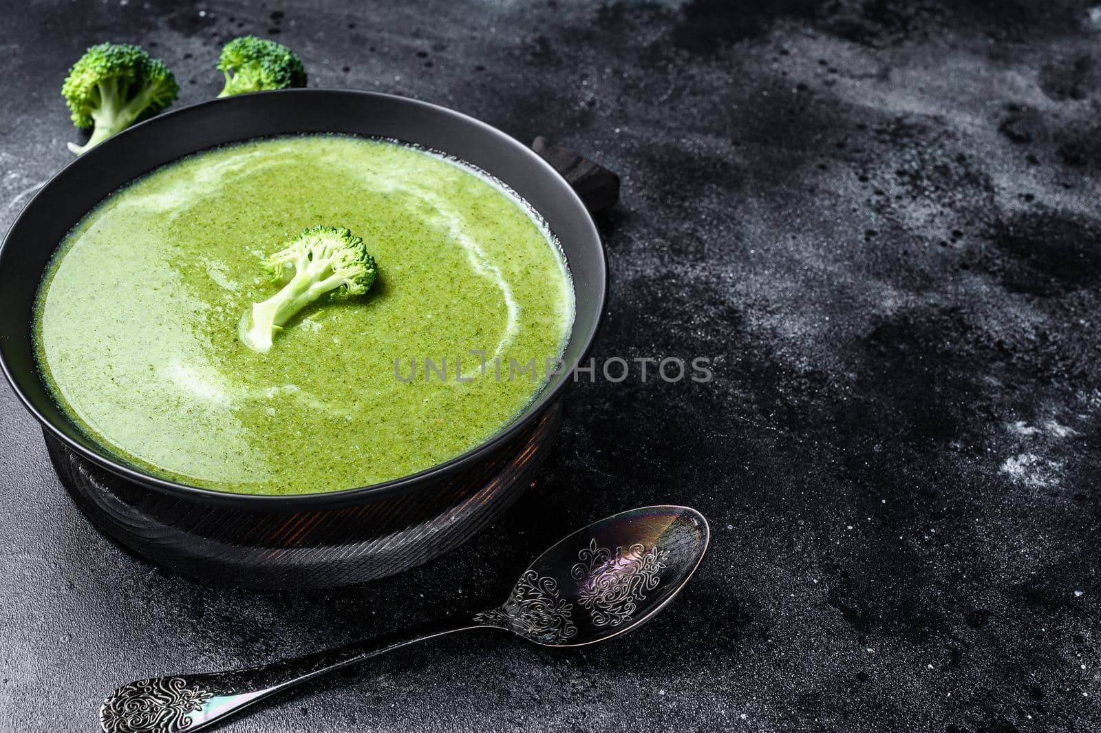 Fresh cream broccoli and pea soup in plate . Black background. Top view. Copy space.