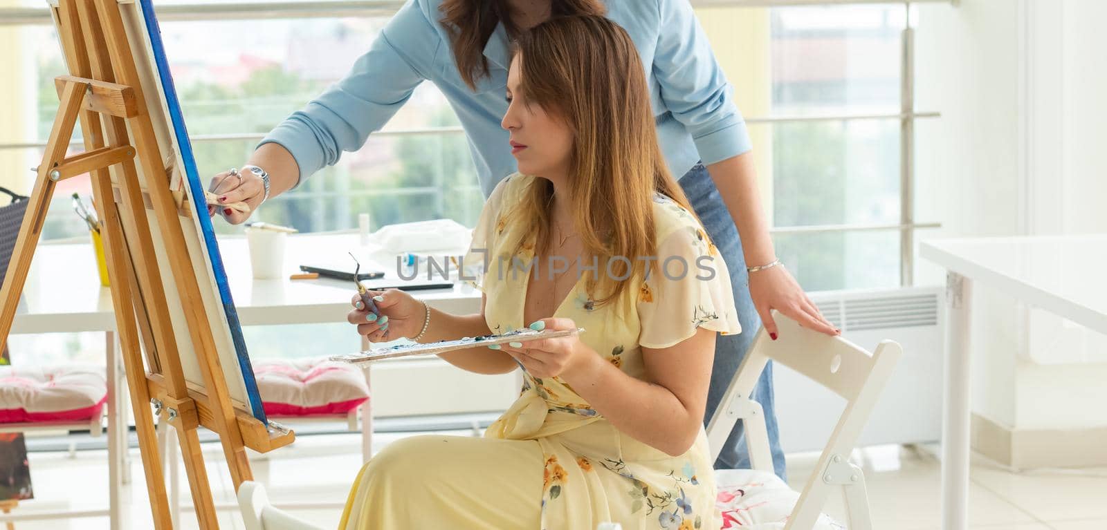 School of art, college of arts, education for group of young students. Happy young woman smiling, girl learning to paint with teacher. by Satura86