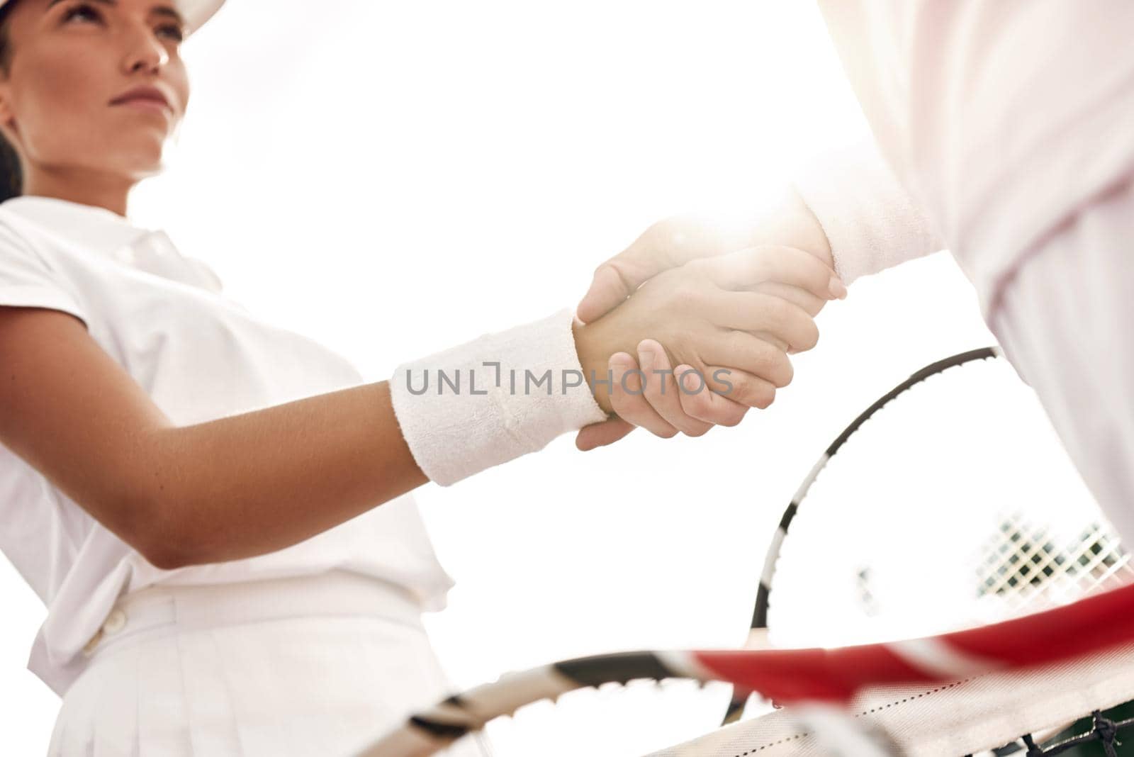 Shaking hands after good game. Close-up of man and woman in wristband shaking hands upon the tennis net