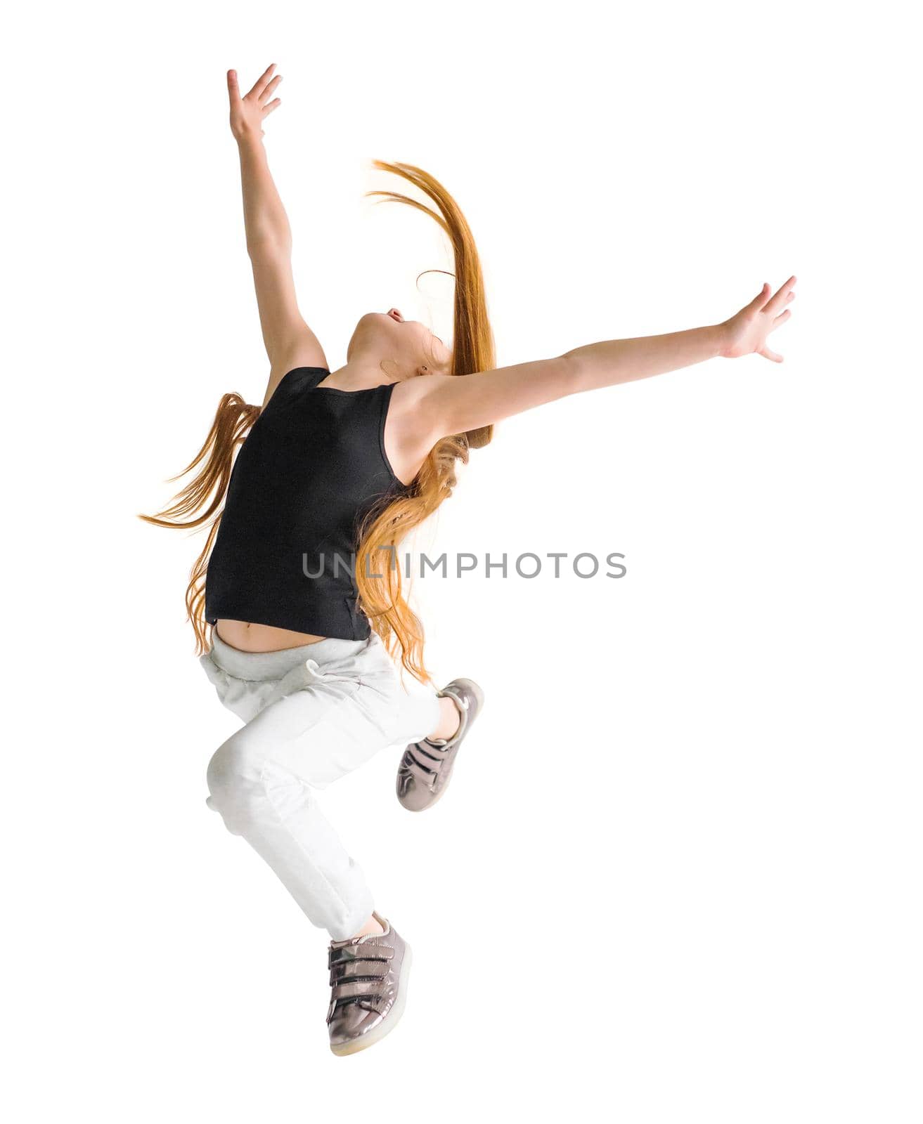 Excited young girl leaping in the air with her hands raised. Sport, training, dancing lifestyle.