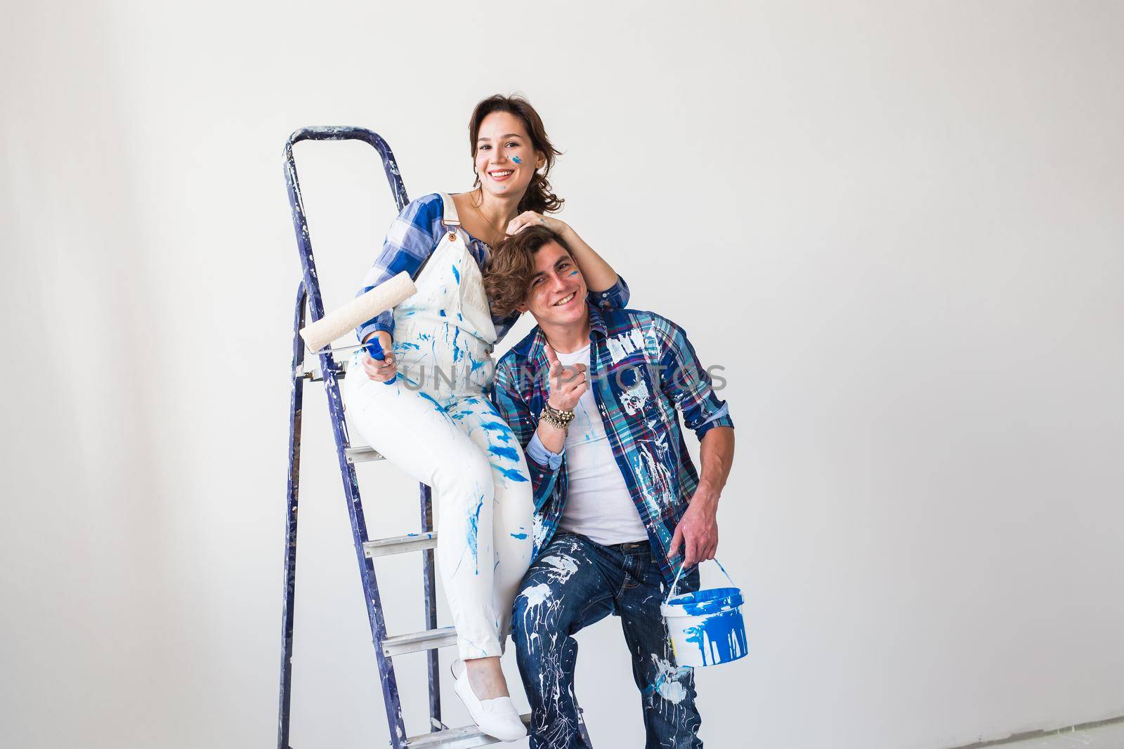 People, redecoration and relationship concept - Young funny couple doing renovation in new apartment.