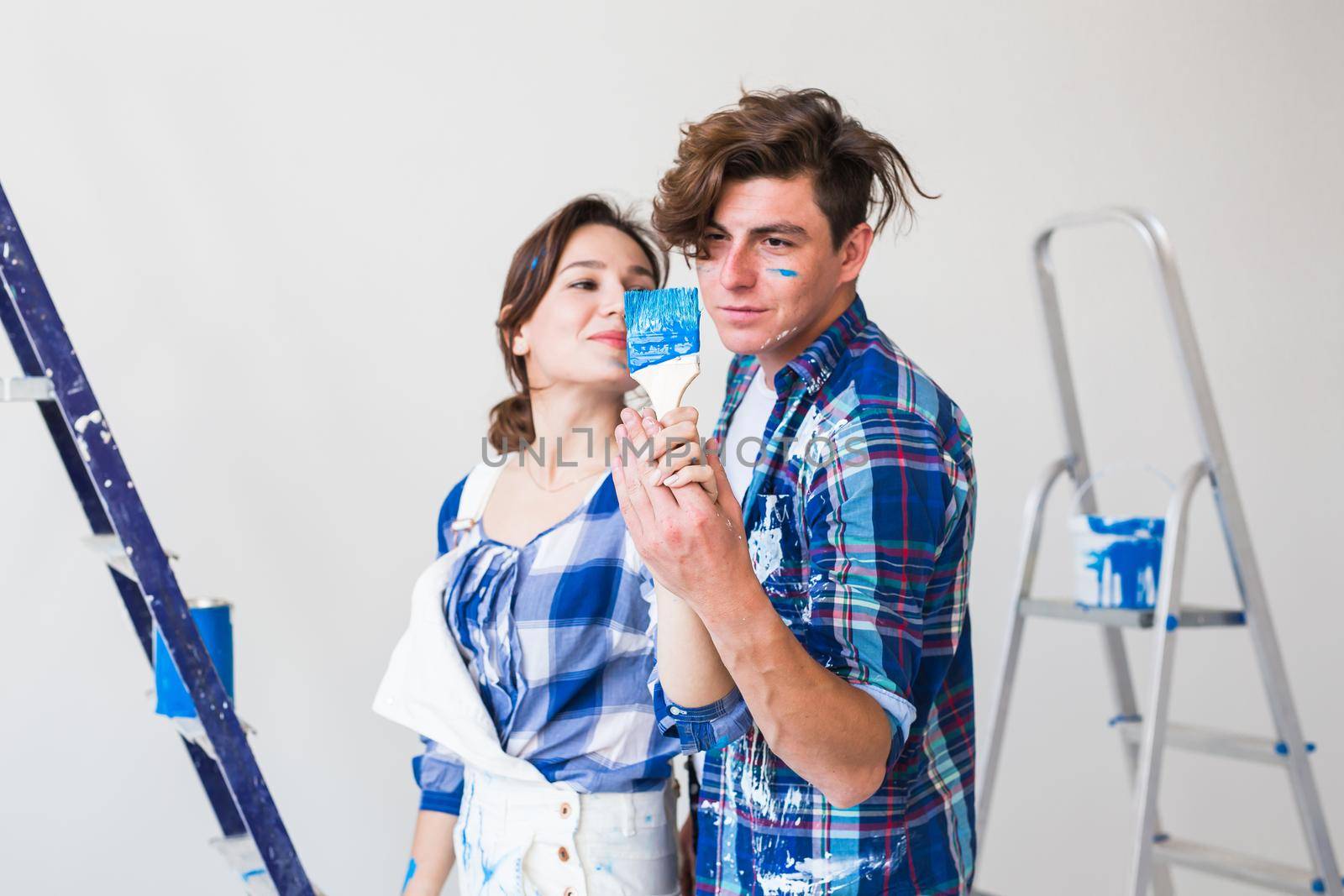People, repair and relationship concept - Young funny couple doing renovation in new apartment.