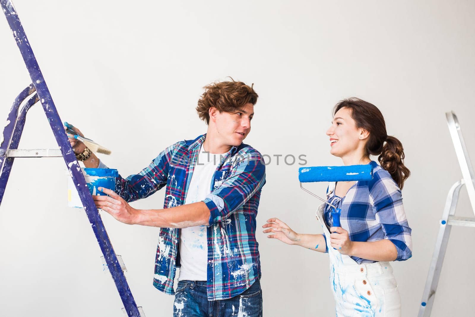 Repair, renovation and love couple concept - young family doing redecoration and painting walls together and laughing
