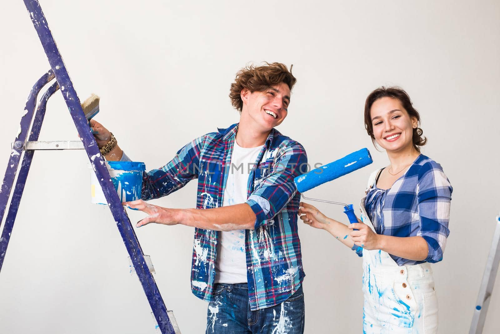 Renovation, repair and people concept - Portrait of couple stained with paint over white background.