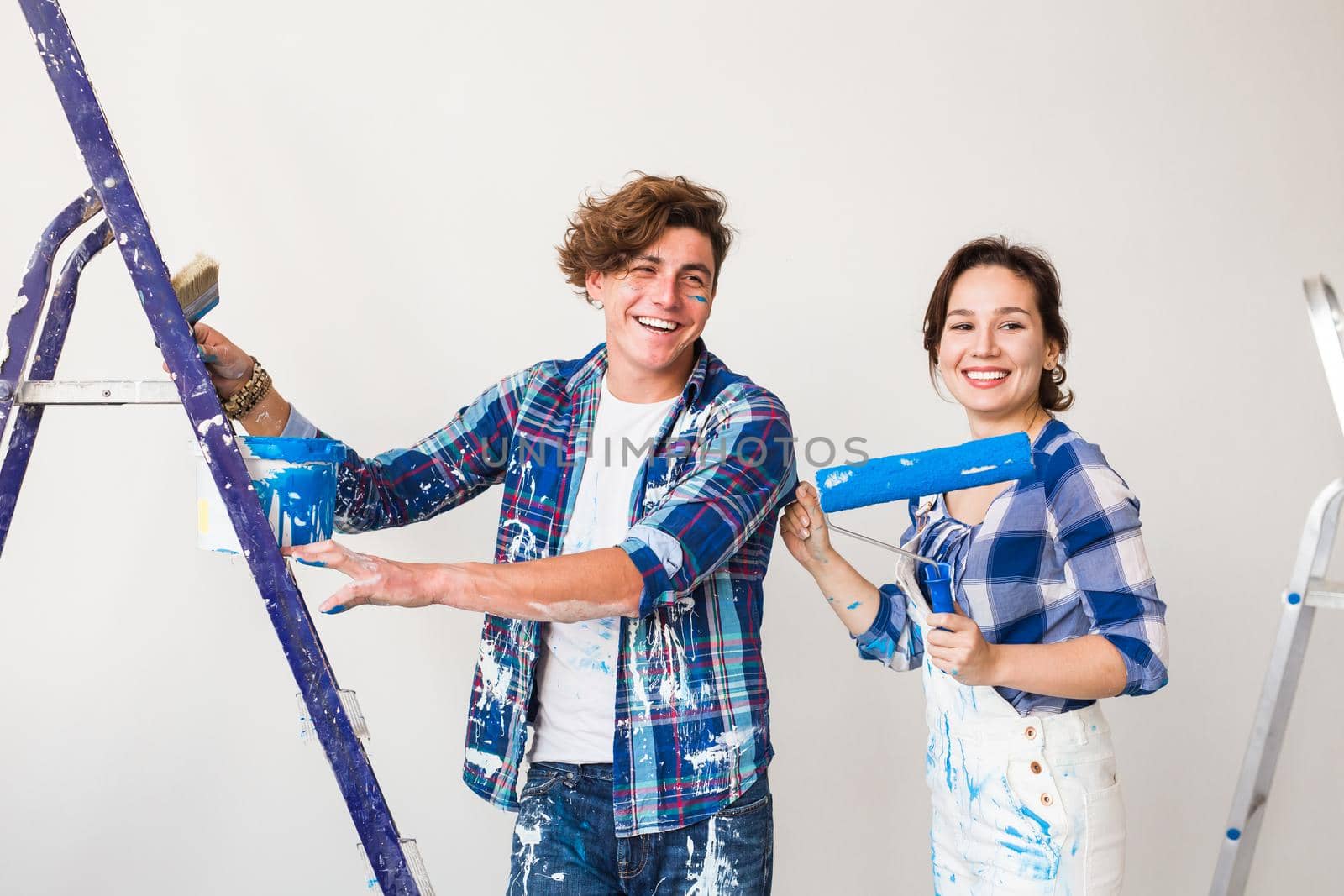 Repair, renovation and love couple concept - young family doing redecoration and painting walls together and laughing