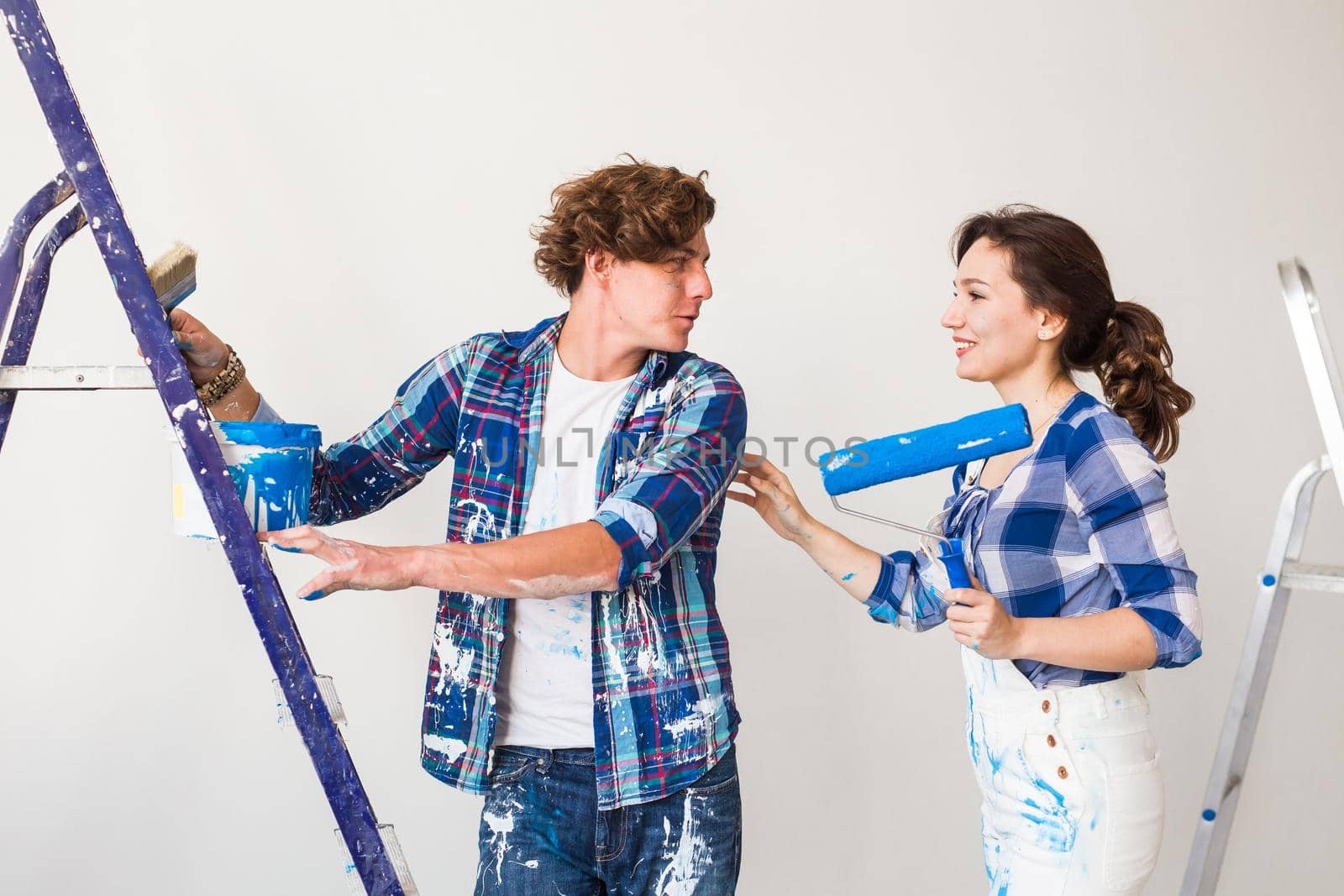 Repair, renovation and love couple concept - young family doing redecoration and painting walls together and laughing