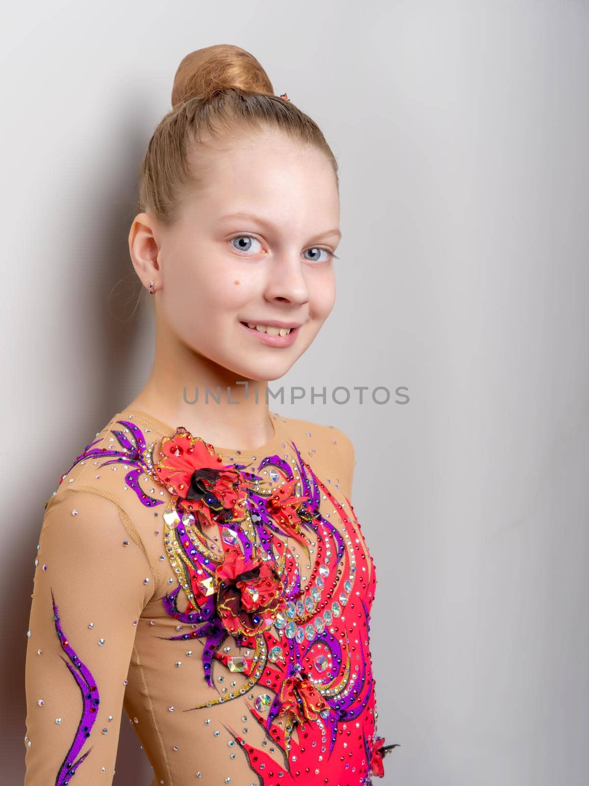 A little girl gymnast in a suit for competitions near the wall. by kolesnikov_studio