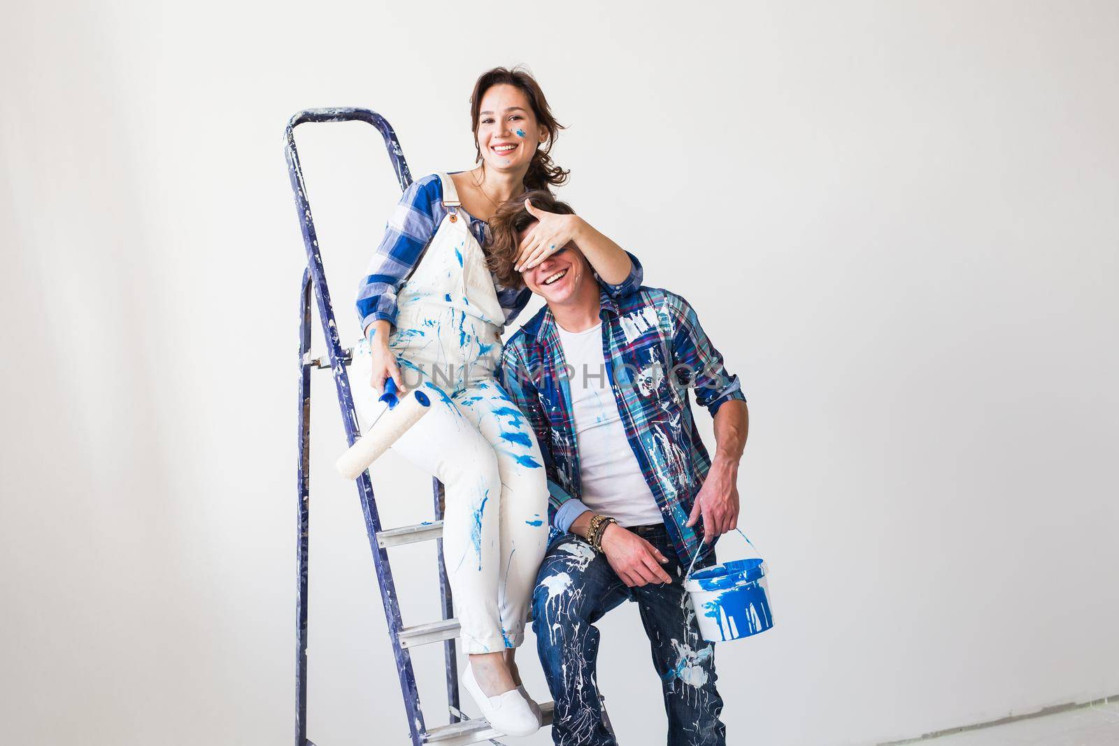 People, repair and relationship concept - Young funny couple doing renovation in new apartment.
