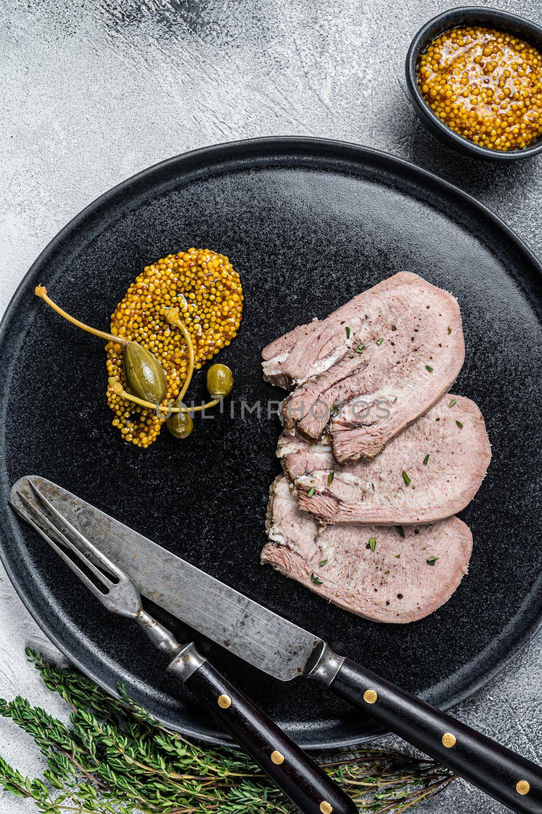 Veal or beef boiled tongue slices on a plate. White background. Top view.