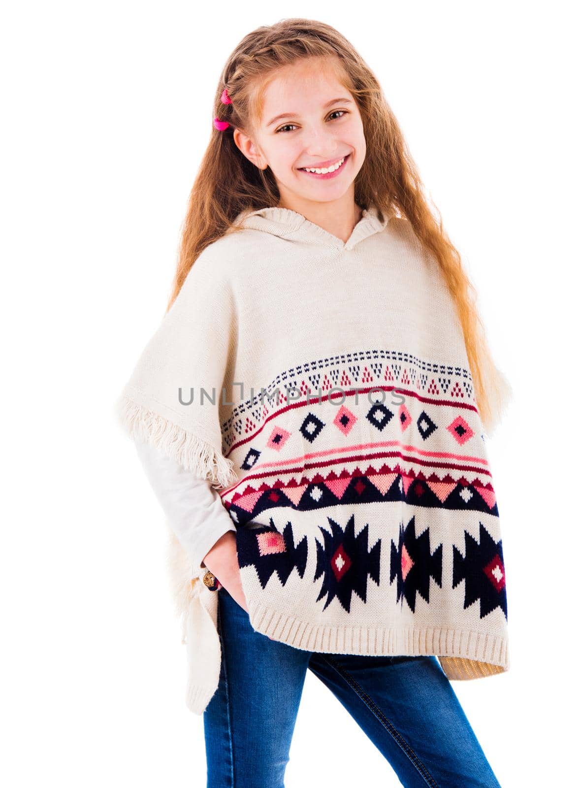 Smiling adorable little girl posing in warm beige poncho and jeans isolated on white background