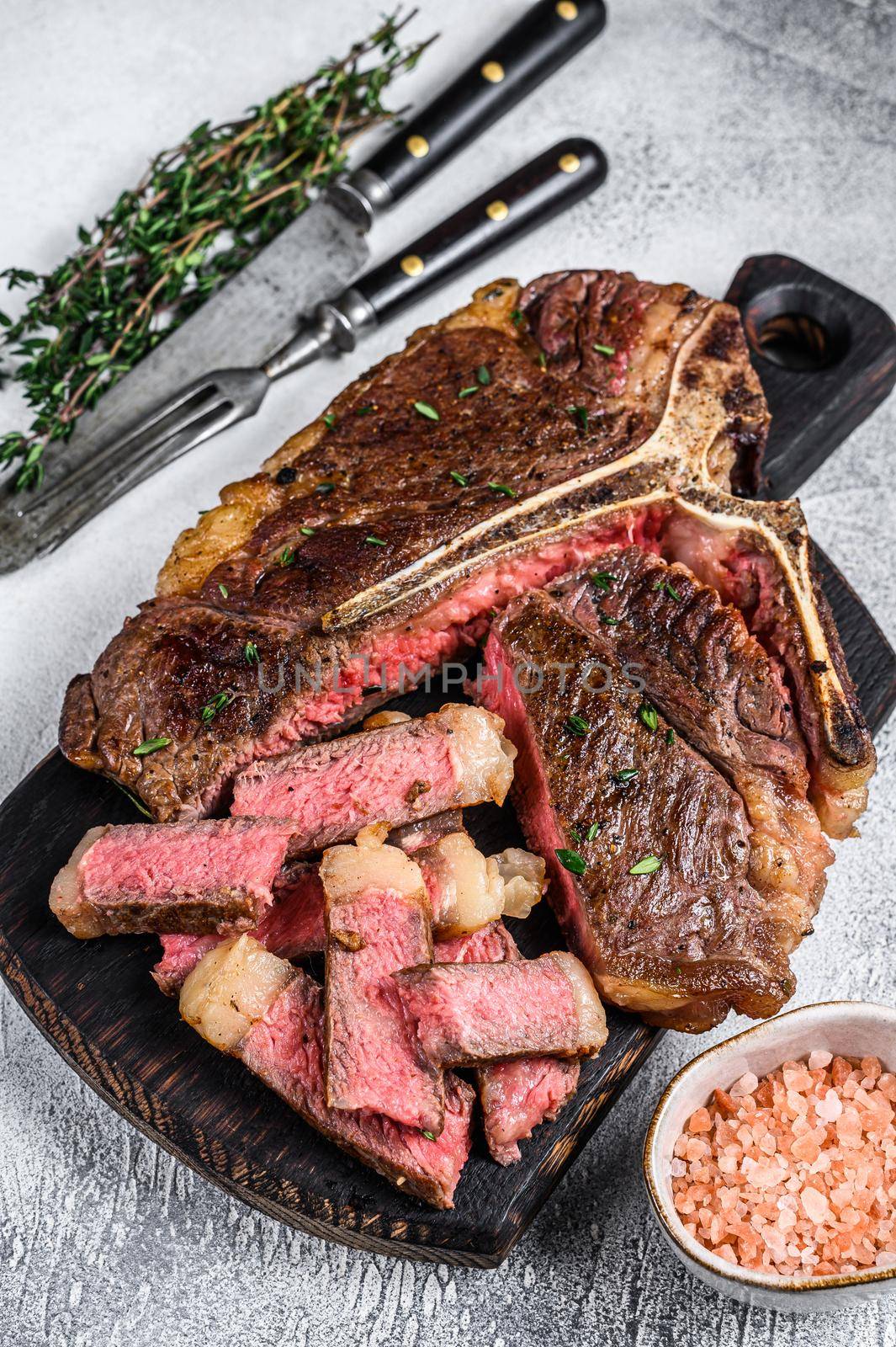 Sliced Grilled T-bone beef meat Steak on a wooden cutting board. White background. Top view by Composter