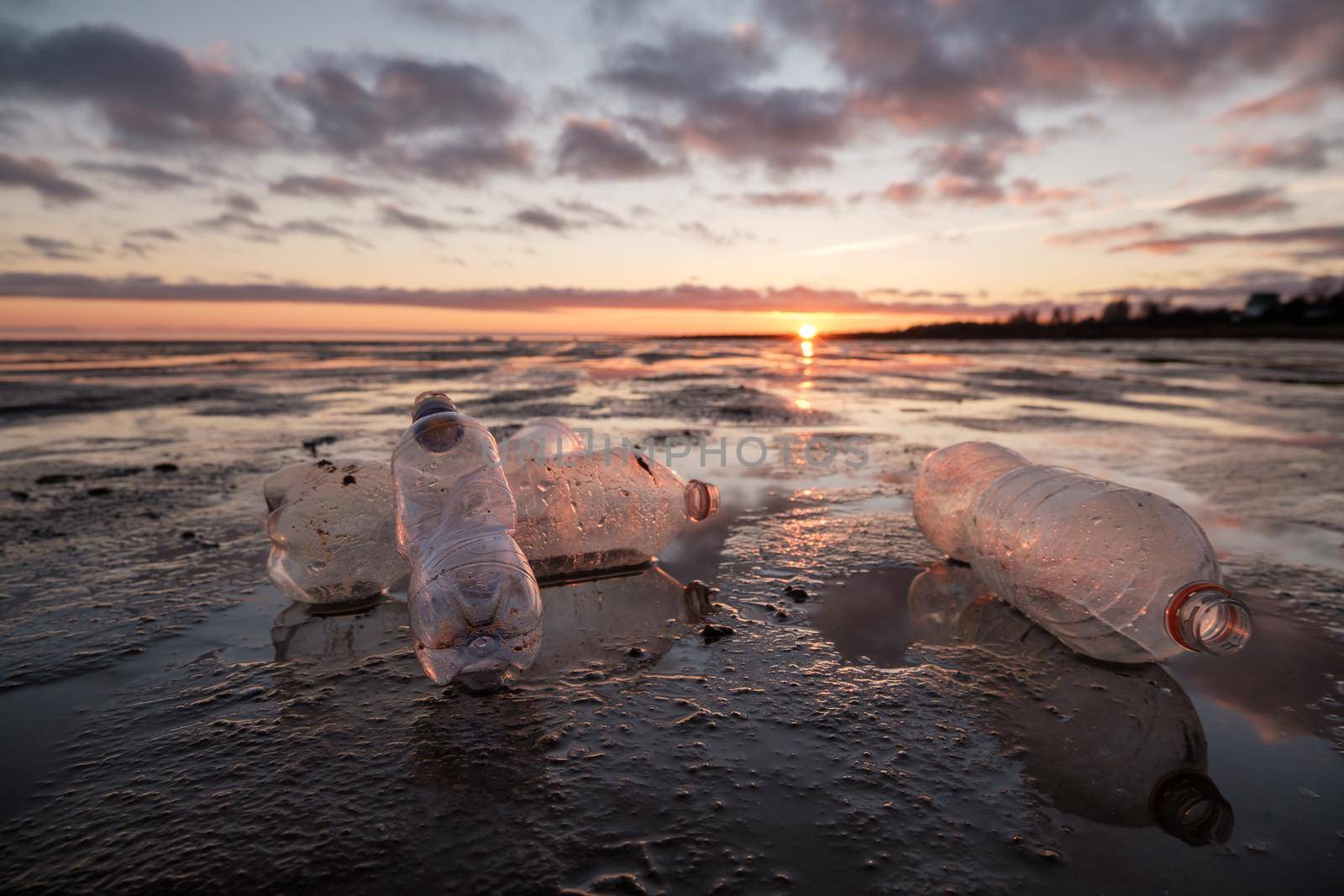 Close-up of plastic bottles thrown on the shore in the backlight by vollirikan