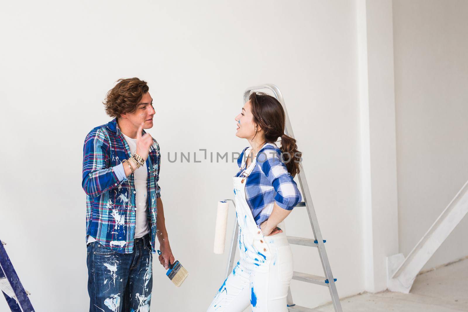 People and interiors concept - Young woman and man discussing new apartment.