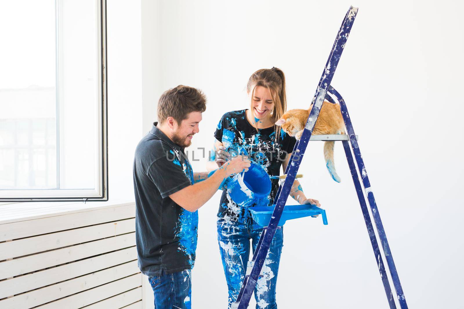 Teamwork and repair concept - young couple with cat doing a renovation in new apartment.