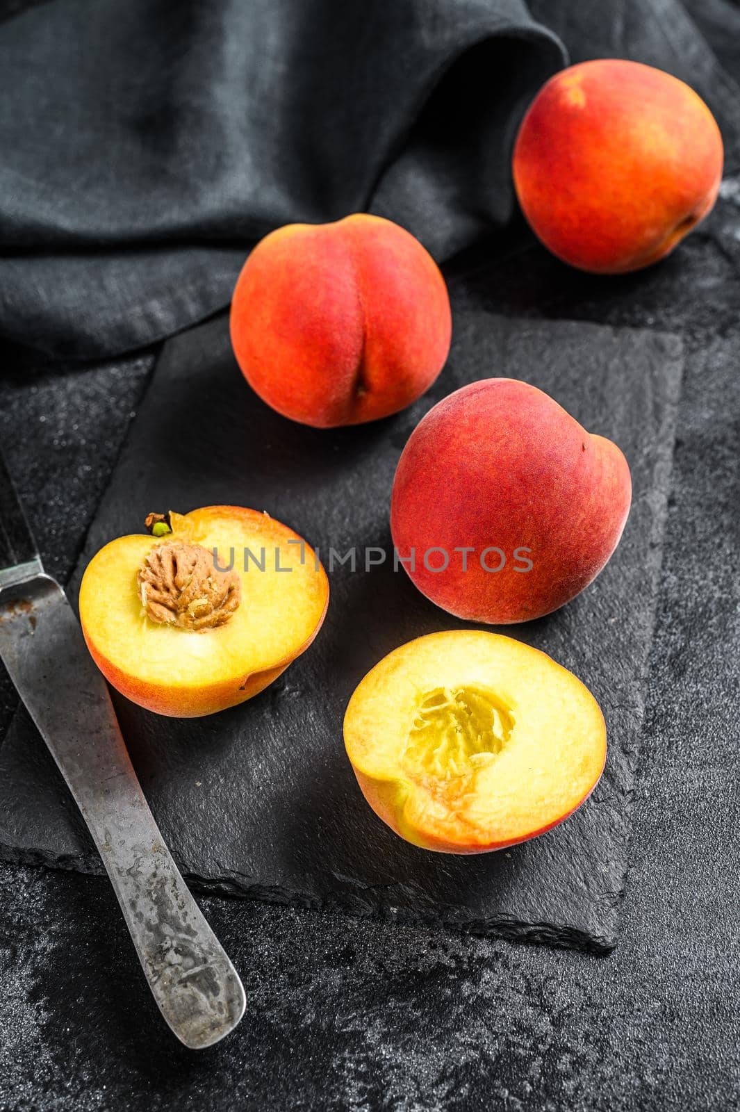 Organic Peaches fruit on a black stone Board. Black background. Top view.