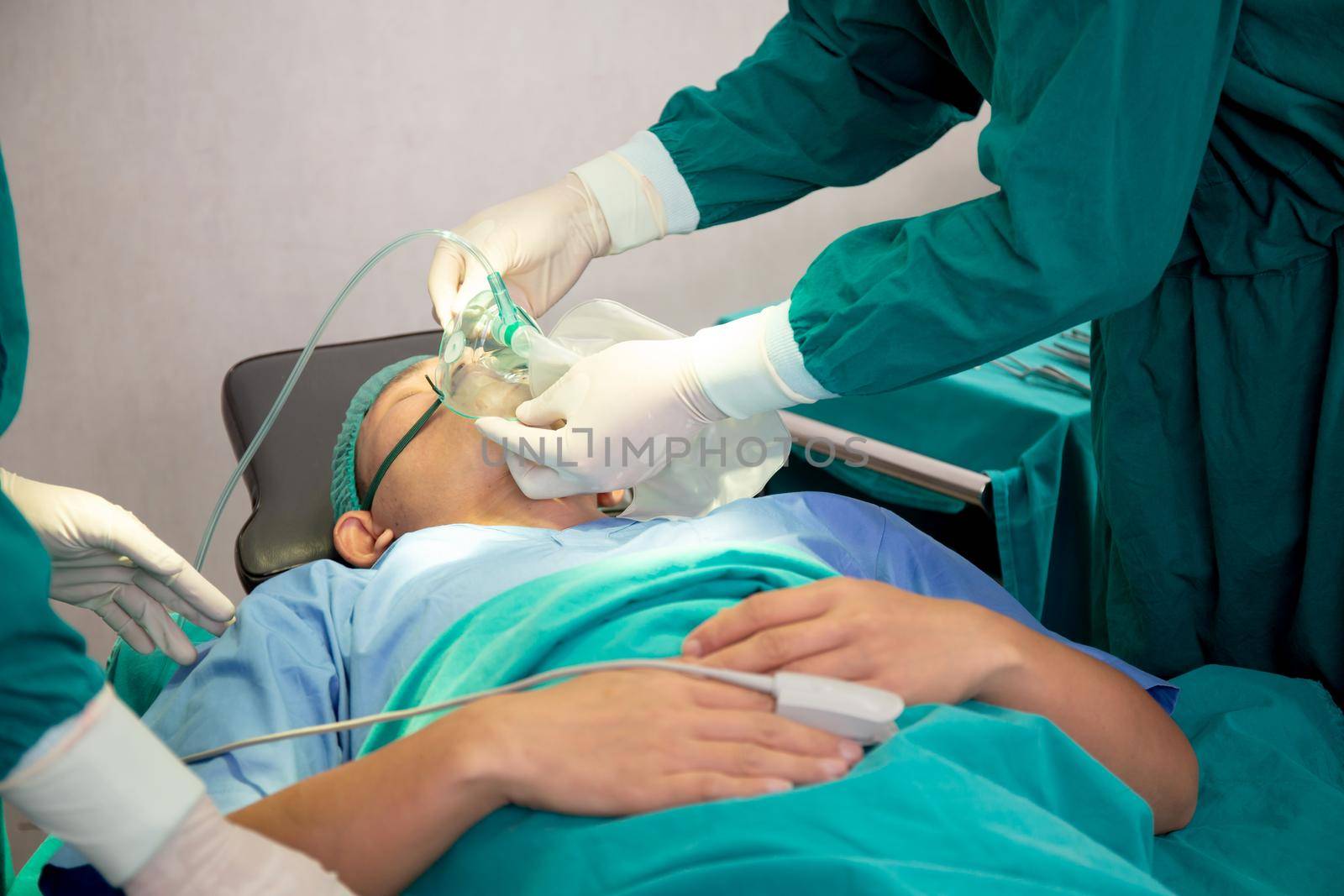 Closeup hands of doctor and assistant holding oxygen mask with patient emergency in the operation room at hospital, surgeon healing and surgery, problem of breathing, instruments medical and health.