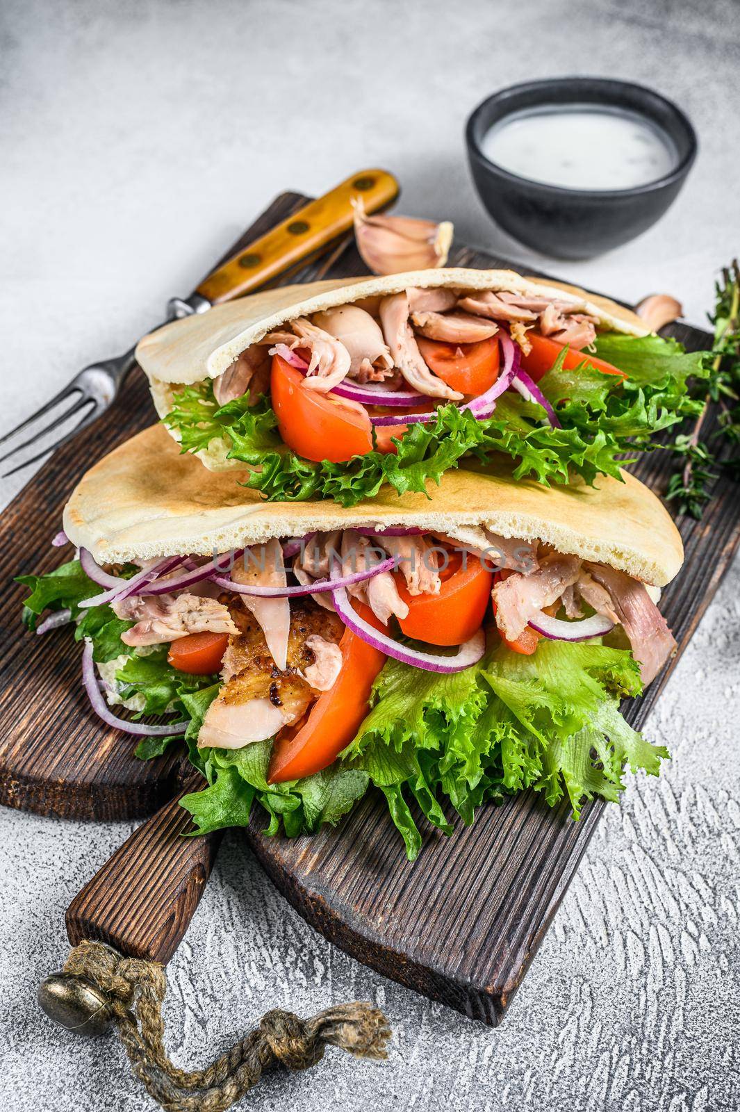 Pita sandwich with roasted chicken, vegetables and delicious sauce. White background. Top view by Composter
