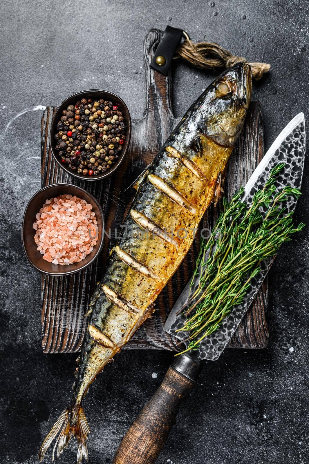 BBQ Grilled mackerel fish with herbs. Black background. Top view.