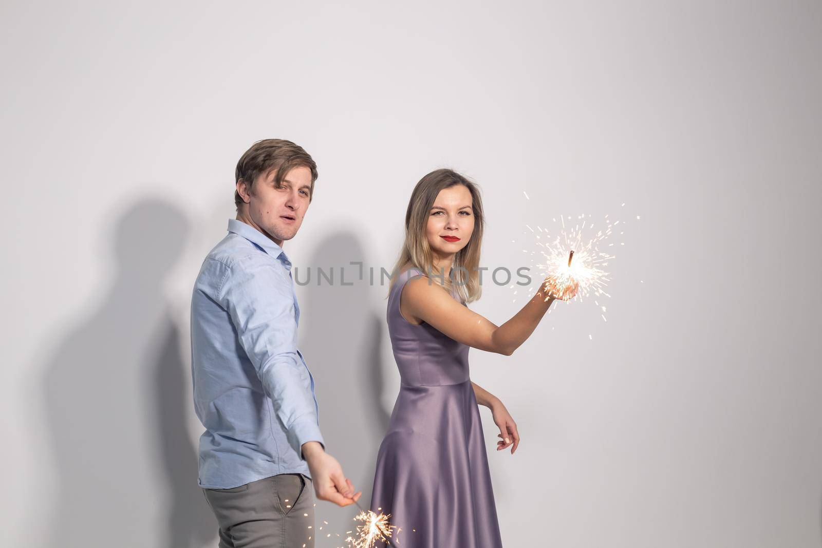 Fun, love and holiday concept - man and woman fooling around with sparklers.