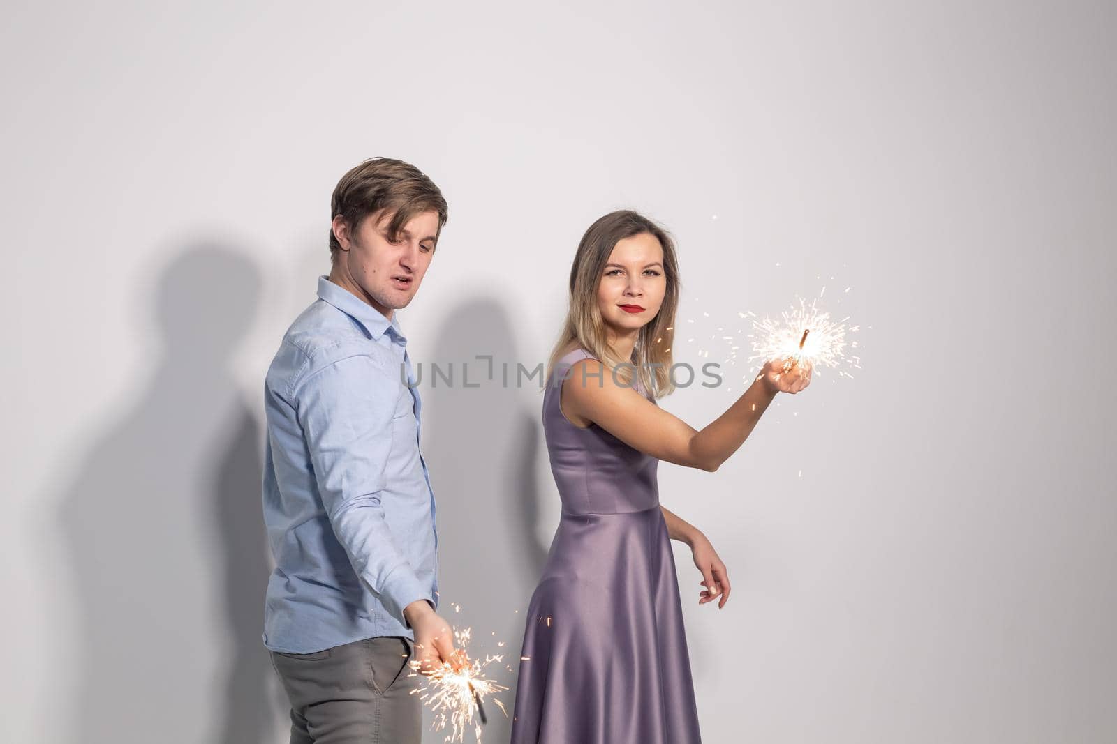 Fun, love and holiday concept - man and woman fooling around with sparklers by Satura86