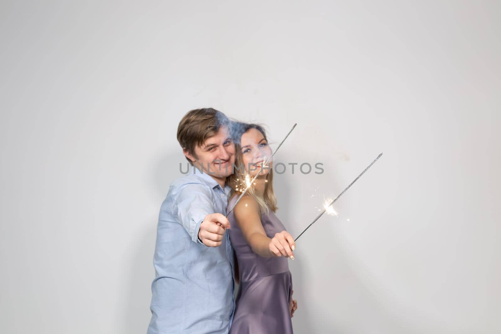 Fun, love and holiday concept - man and woman fooling around with sparklers.