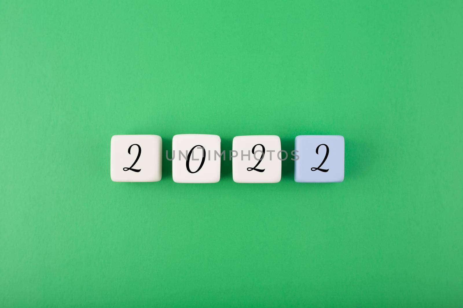 2022 numbers on white cubes against green background. Minimal elegant business style concept of New Year
