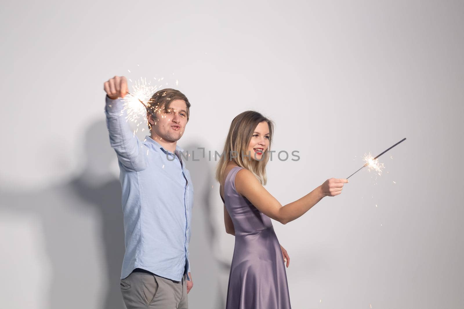 Fun, love and holiday concept - man and woman fooling around with sparklers by Satura86