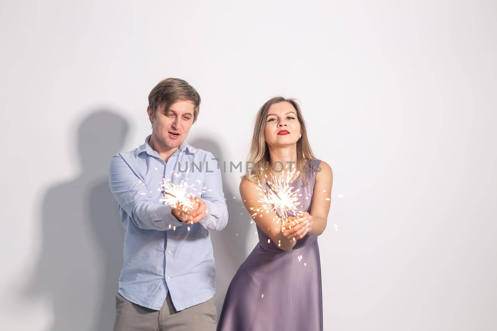 Fun, love and holiday concept - man and woman fooling around with sparklers.