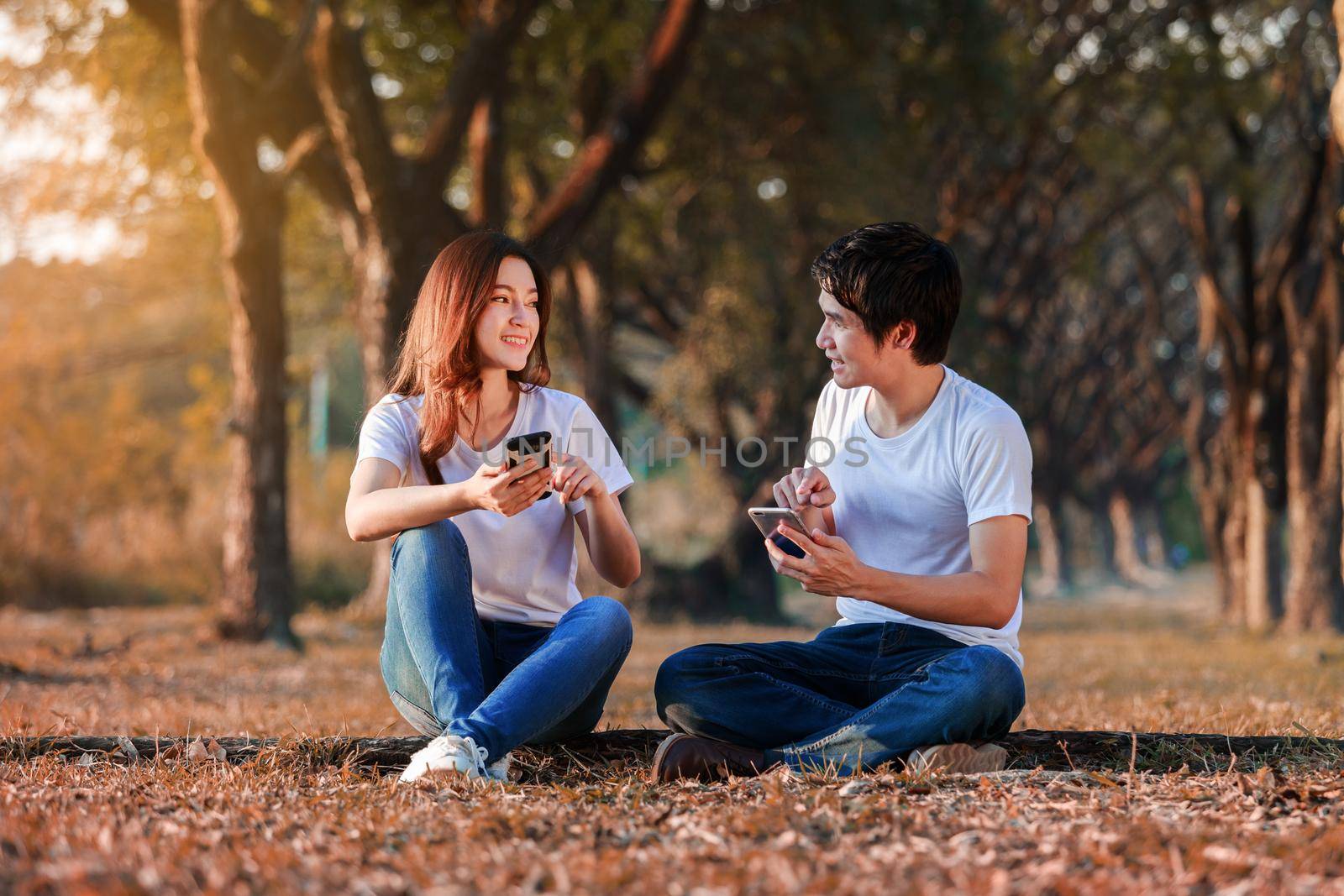 couple using mobile phone and talking in the park