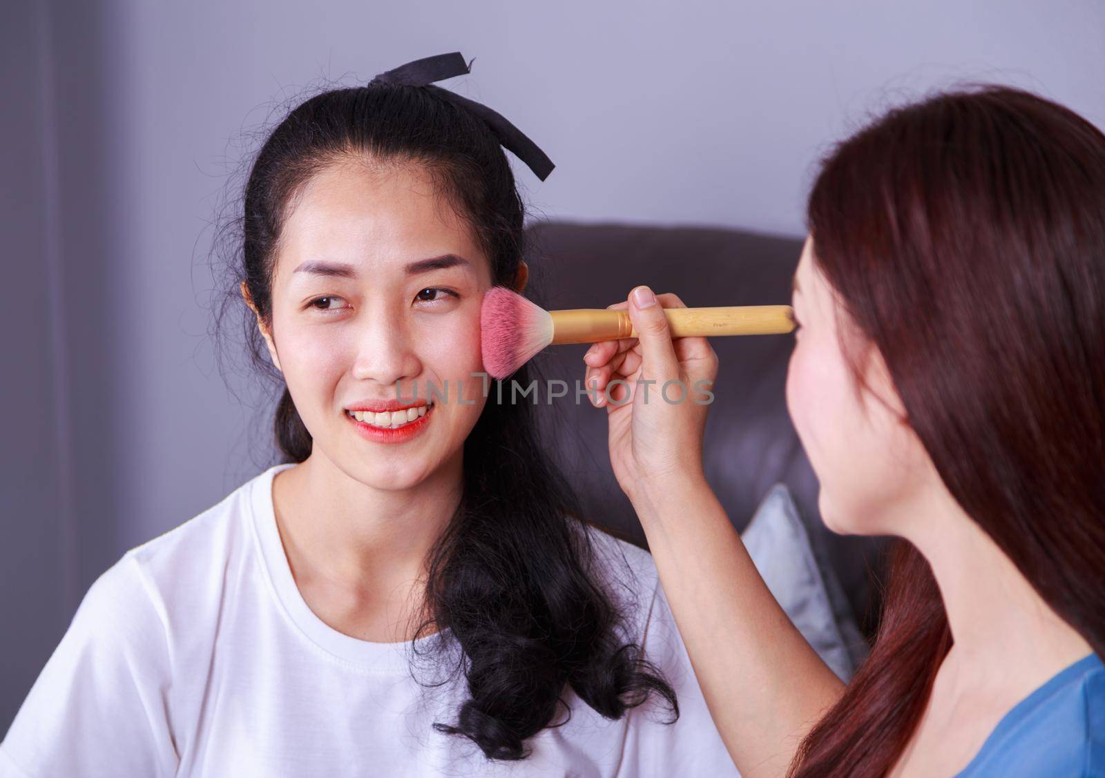 young woman using brush makeup on face her friend