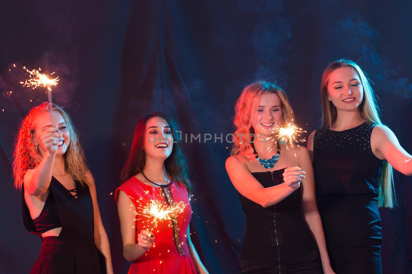 Party, holidays, new year, christmas and nightlife concept - happy young women dancing at night club disco, close-up.