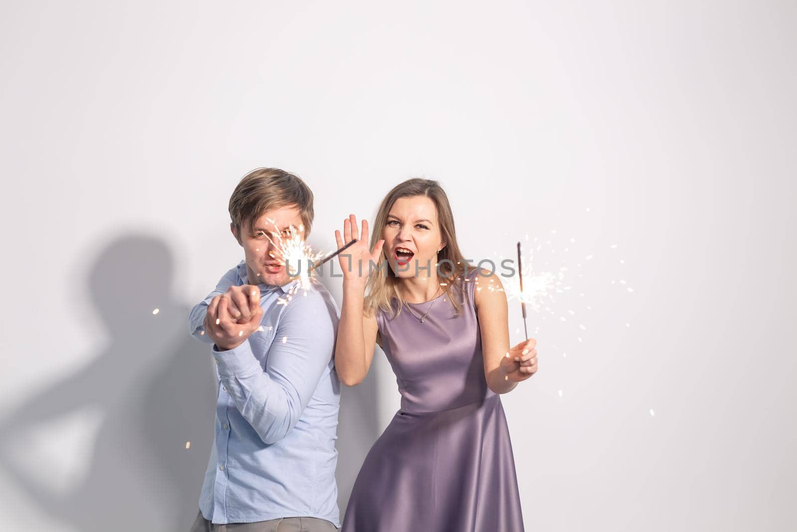 Fun, love and holiday concept - man and woman fooling around with sparklers.