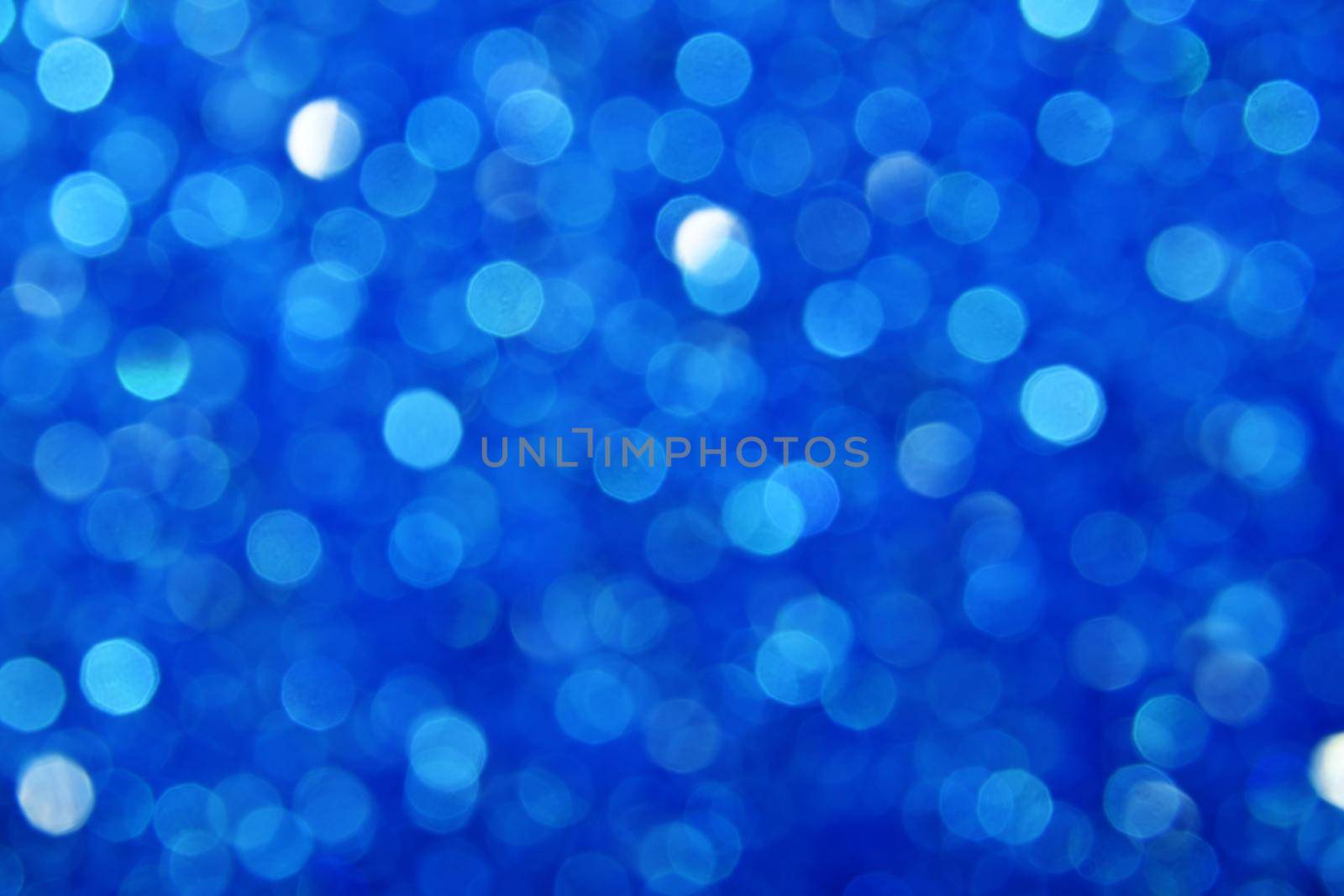 Abstract background of cold winter blue bokeh defocused blurred lights and glitter sparkles