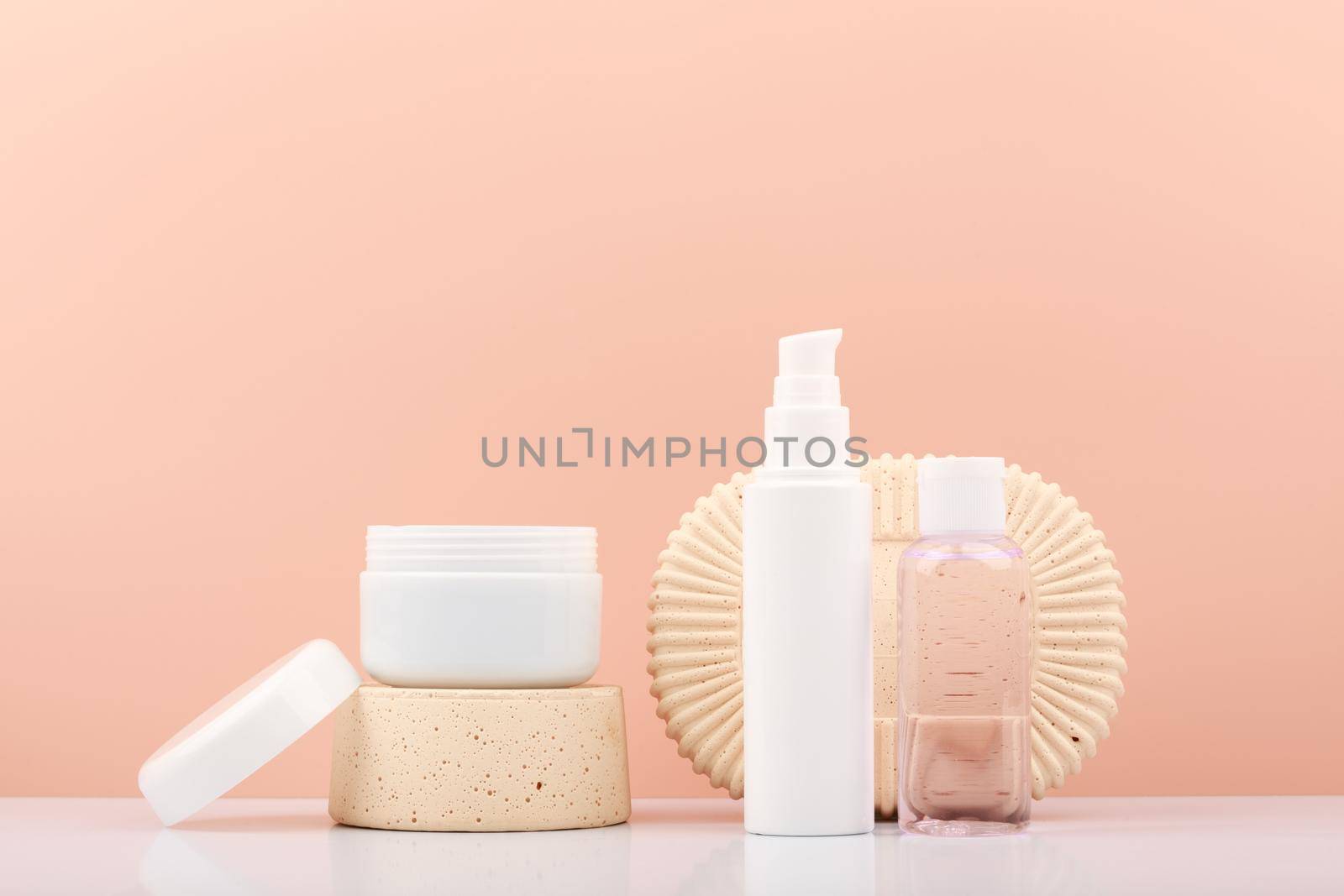 Set of skin care products on gypsum shapes on white table against bright beige background with copy space. Products for daily skin care routine and luxury skin treatment