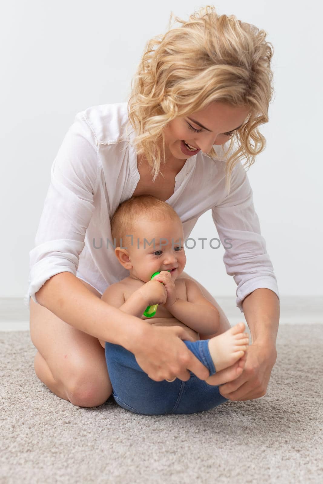 family, child and parenthood concept - happy smiling young mother playing with little baby at home.