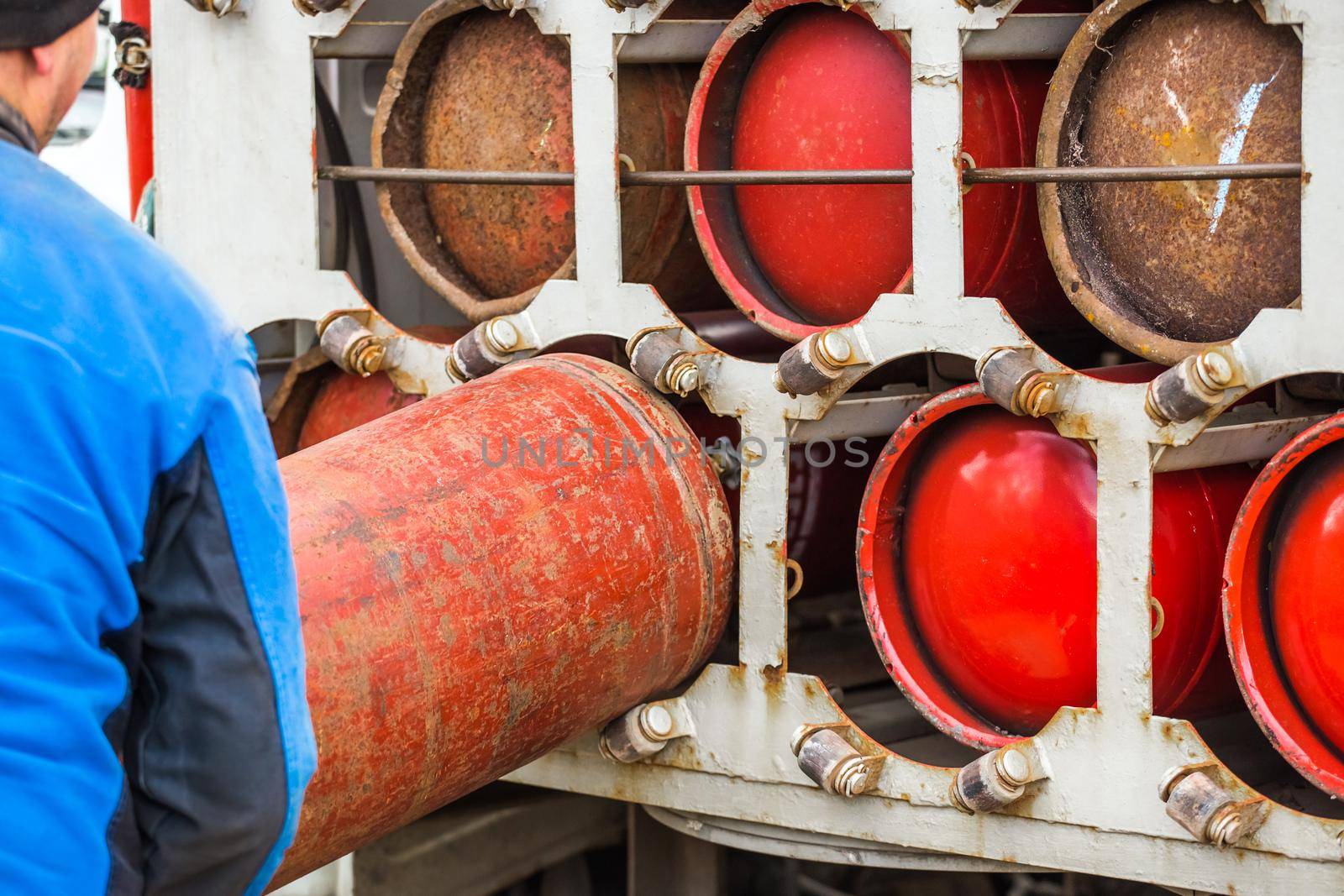 Male industrial worker puts a gas cylinder into a gas machine. Equipment for the safe transportation of propane gas bottles.