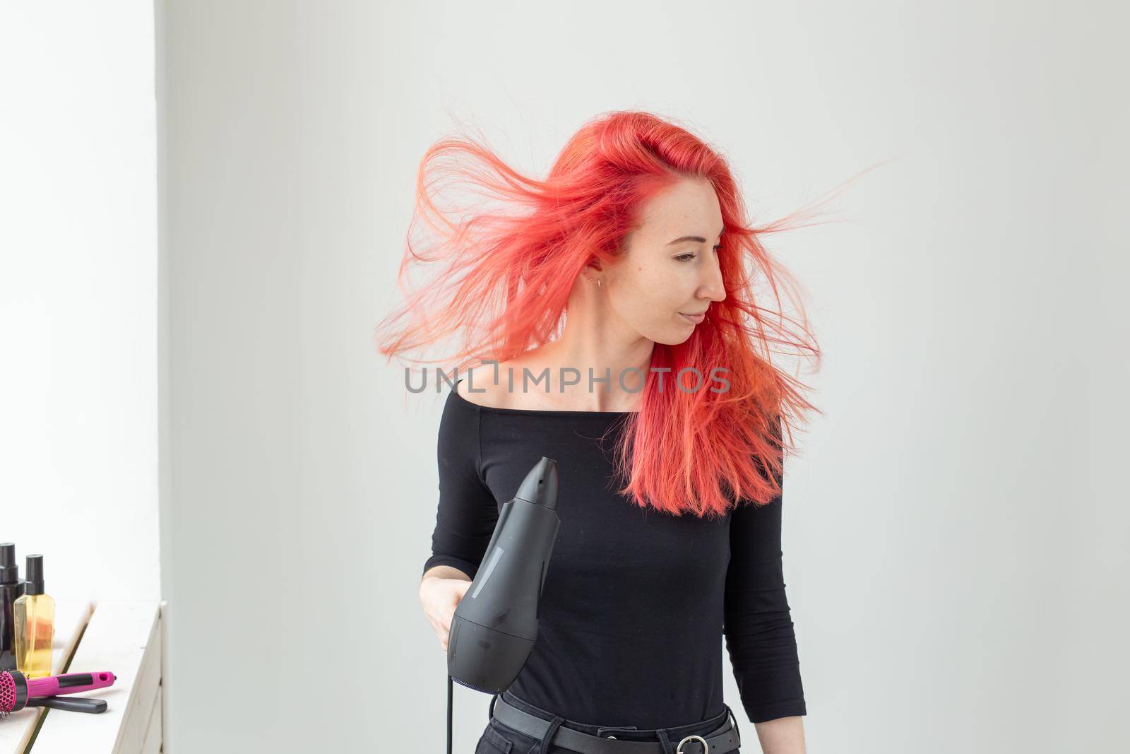 Hairdresser, beauty salon and people concept - young woman hair stylist with hair dryer on white background.
