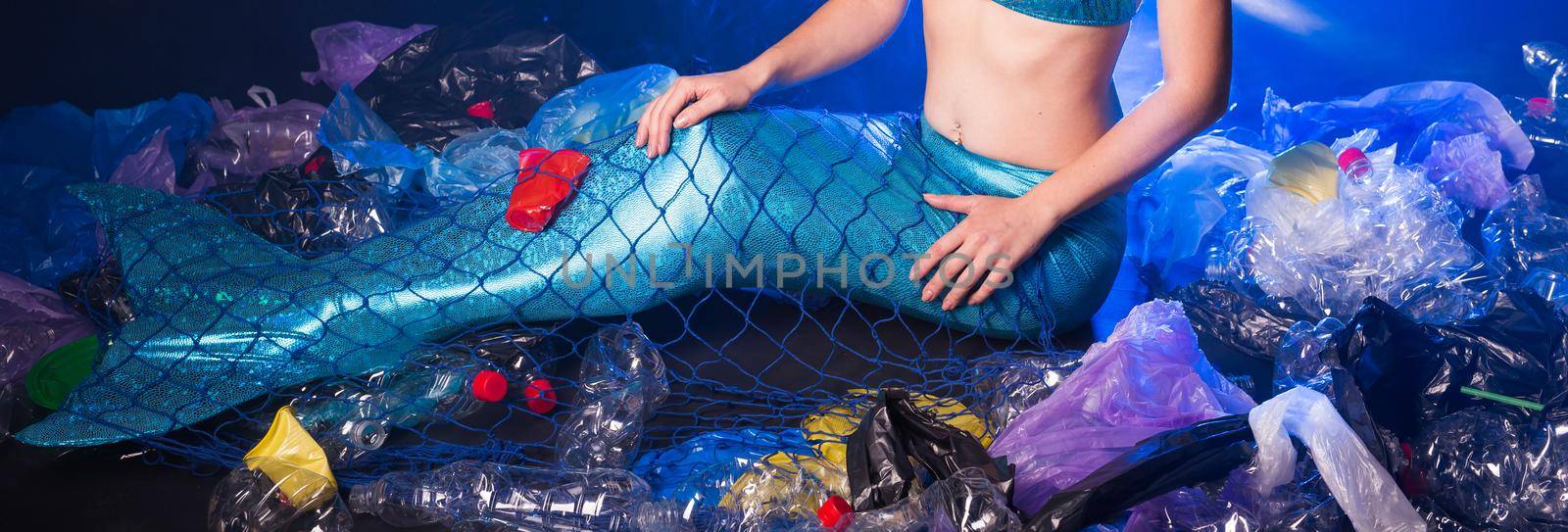 Close-up of fairytale mermaid in polluted ocean. Plastic trash and garbage in water. Environmental problem, plastic bag and bottles polluting a coral reef. by Satura86