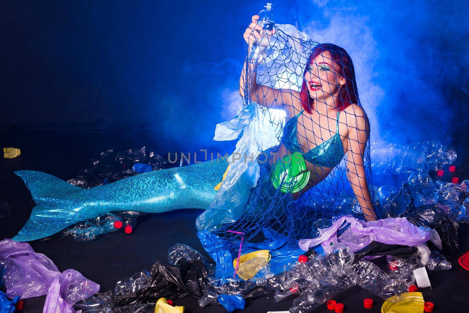Fantasy stupid mermaid in deep ocean. Plastic trash and bottles pollution in ocean. Ecocatastrophe, garbage and plastic recycling.