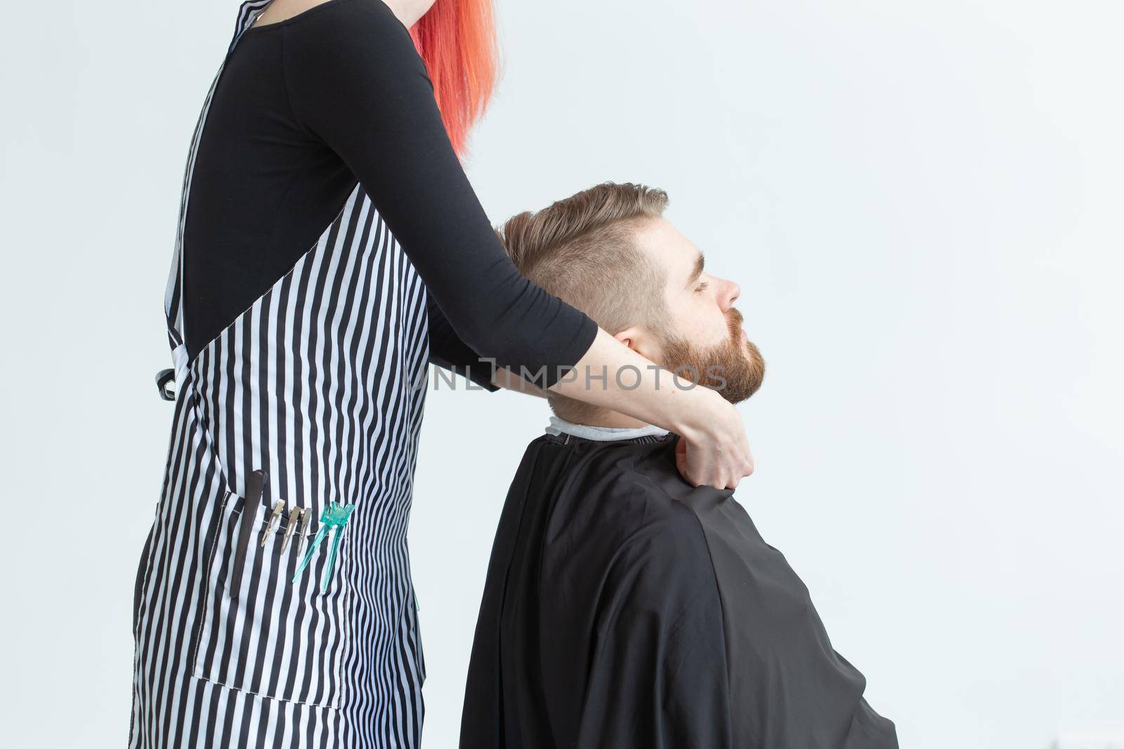 Hairdresser, hairstylist and barber shop concept - woman hairstylist cutting a bearded man.
