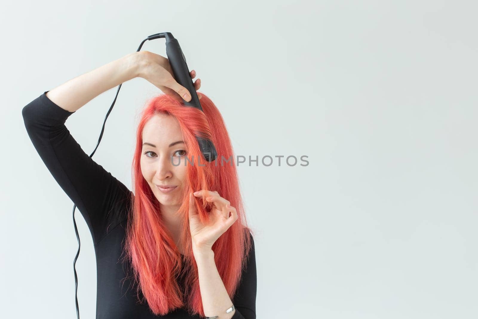 Style, fashion, hairdresser and people concept - stylish red-haired woman with curling iron on white background.