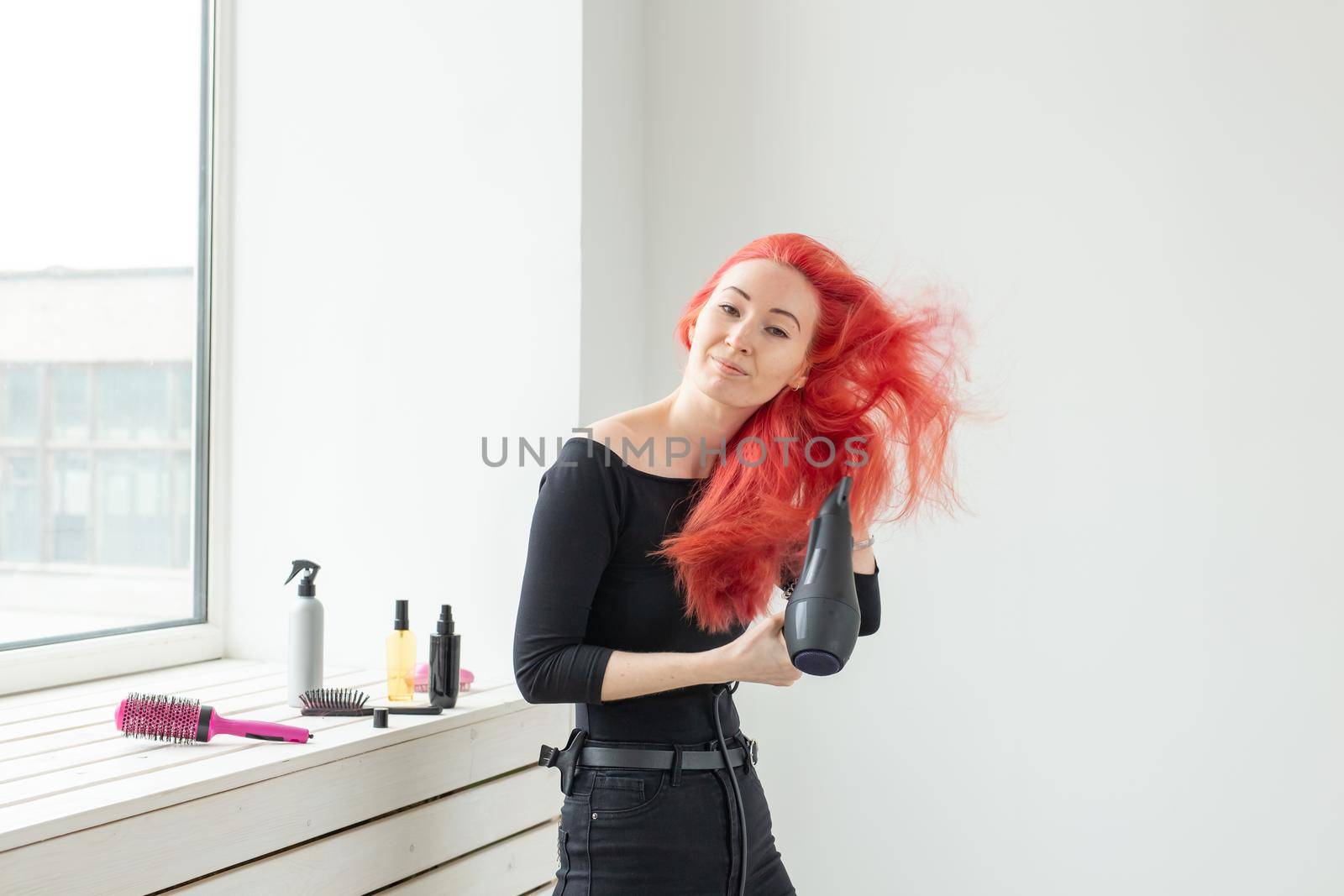 Stylist, fashion, hairdresser, people concept - woman drying her colored hair.