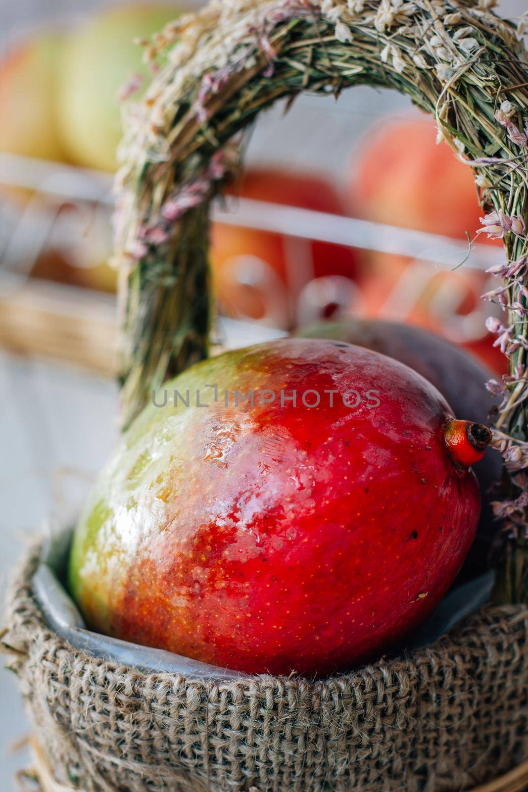 Ripe mango in a basket over a white wooden background